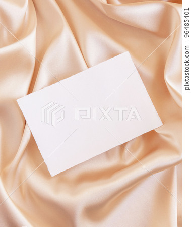 Blank card on beige silky fabric drapery top view, greeting or wedding mockup 96485401