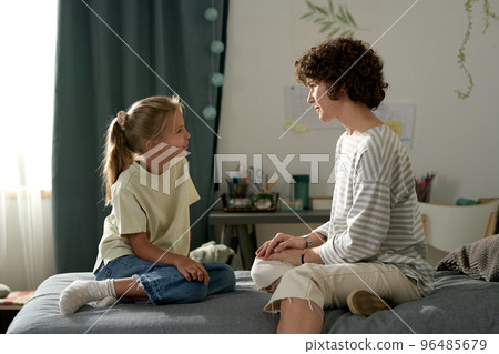 Mother having openly conversation with her daughter while they sitting on bed in bedroom Mother having openly conversation with her daughter while they sitting on bed in bedroom 96485679