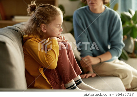 Little boy sitting on sofa without mood and having no desire to talk to his mom Little boy sitting on sofa without mood and having no desire to talk to his mom 96485737