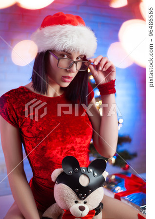 sexy woman in a red bodysuit with a Santa Claus hat on the background of a Christmas tree 96486566