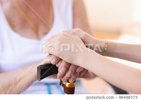 Young woman putting hands on granny hands, supporting gesture Young woman putting hands on granny hands, supporting gesture 96486573