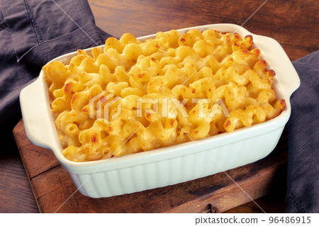 Macaroni and cheese pasta in a casserole, on a rustic wooden table Macaroni and cheese pasta in a casserole, on a rustic wooden table 96486915
