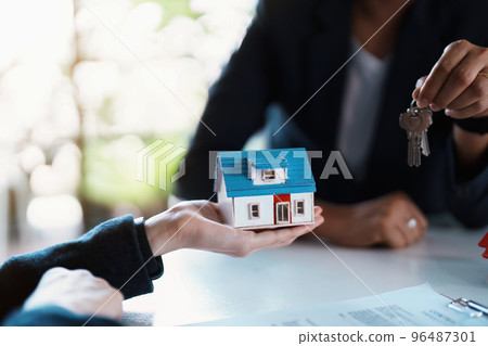 Accountant, businessman, real estate agent, Asian business woman handing keys to customers along with house after customers to sign. 96487301