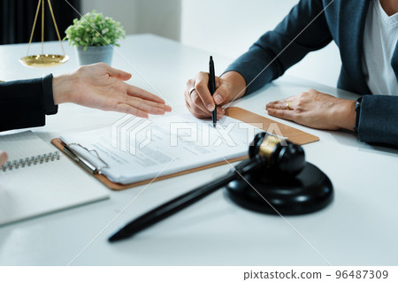 The signing of important documents between the lawyer and the client to enter into an agreement in a court case. The signing of important documents between the lawyer and the client to enter into an agreement in a court case. 96487309