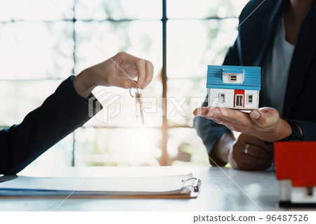 Accountant, businessman, real estate agent, Asian business woman handing keys to customers along with house after customers to sign. 96487526