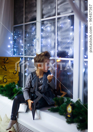 Cute little girl sitting by the window and waiting for Holiday 96487567