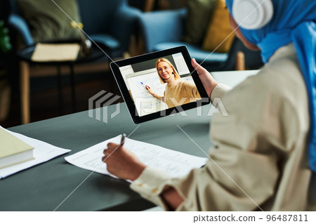 Focus on tablet screen with blond confident teacher pointing at whiteboard 96487811