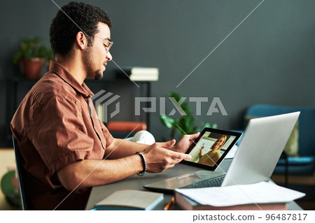 Young confident man looking at mature teacher on tablet screen Young confident man looking at mature teacher on tablet screen 96487817