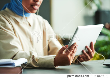 Hands of young Muslim tutor holding tablet in front of herself 96487902