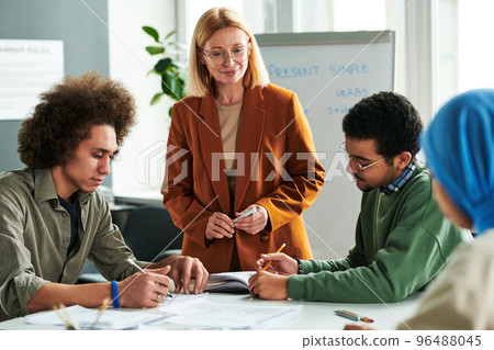 Confident teacher standing in front of intercultural students Confident teacher standing in front of intercultural students 96488045