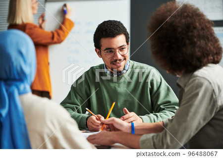 Happy young man in eyeglasses communicating with another student Happy young man in eyeglasses communicating with another student 96488067