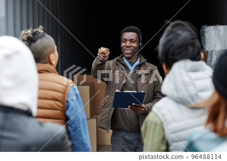 Smiling auctioneer standing by container Smiling auctioneer standing by container 96488114