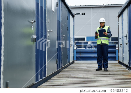 Female worker holding clipboard at shipping docks Female worker holding clipboard at shipping docks 96488242