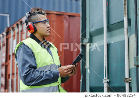 Female worker wearing ear protection at shipping docks 96488254