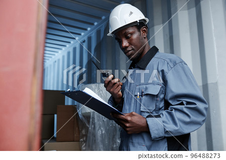 Male worker checking containers at shipping dock 96488273