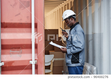 Male worker checking containers at shipping dock 96488276