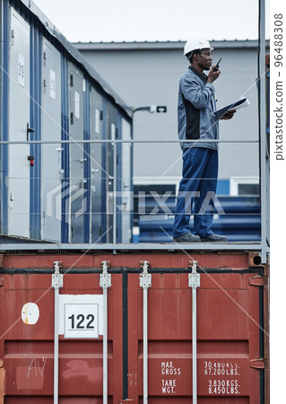 Worker standing on containers in shipping docks 96488308