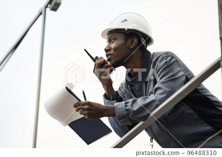 Male worker wearing hardhat and using radio 96488310