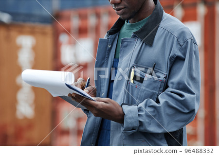 Man wearing hardhat and holding clipboard at shipping docks Man wearing hardhat and holding clipboard at shipping docks 96488332