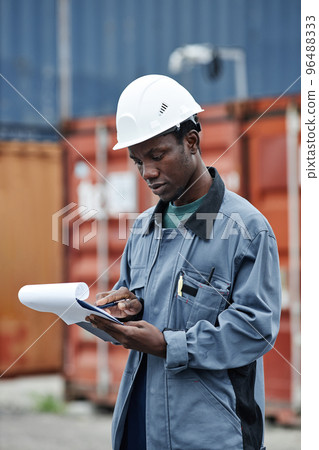 Black man wearing hardhat working at shipping docks 96488333