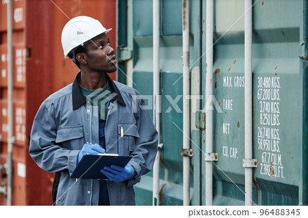 Young black man wearing hardhat while working at shipping dock 96488345