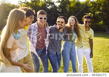 Young happy multiracial people men and woman walk around summer park together with friends 96488373