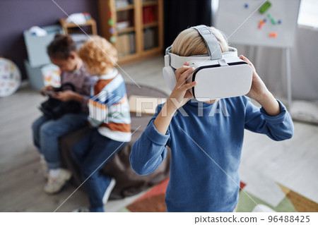 Blond little boy in vr headset standing in front of camera 96488425