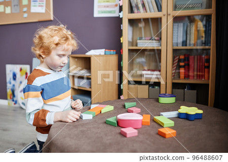 Cute little boy with ginger hair playing with wooden blocks Cute little boy with ginger hair playing with wooden blocks 96488607