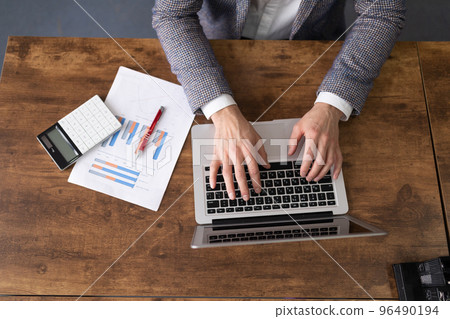 a businessman works at a laptop nearby lie documents calculator top view 96490194