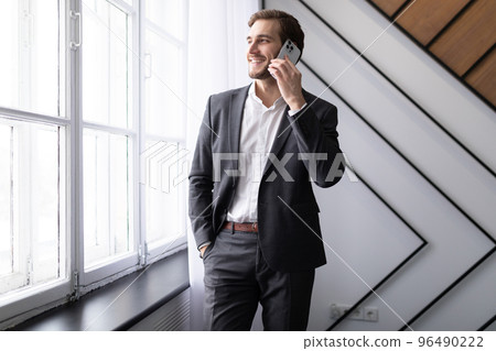 young businessman talking on a mobile phone looking out the window in the office 96490222