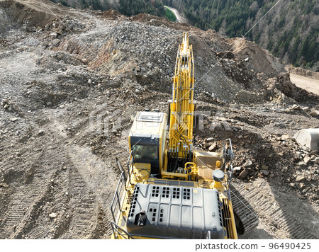 Industrial mine excavators are digging the soil in the construction site and loading trucks. Aerial drone top view. Industrial mine excavators are digging the soil in the construction site and loading trucks. Aerial drone top view. 96490425