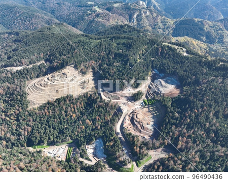 Industrial mine excavators are digging the soil in the construction site and loading trucks. Aerial drone top view. Industrial mine excavators are digging the soil in the construction site and loading trucks. Aerial drone top view. 96490436
