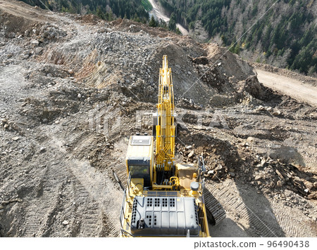 Industrial mine excavators are digging the soil in the construction site and loading trucks. Aerial drone top view. Industrial mine excavators are digging the soil in the construction site and loading trucks. Aerial drone top view. 96490438