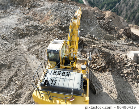 Industrial mine excavators are digging the soil in the construction site and loading trucks. Aerial drone top view. Industrial mine excavators are digging the soil in the construction site and loading trucks. Aerial drone top view. 96490439