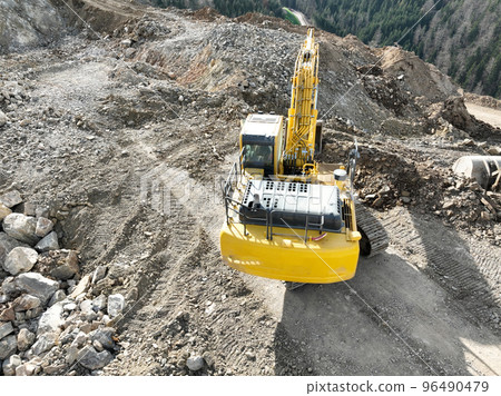 Industrial mine excavators are digging the soil in the construction site and loading trucks. Aerial drone top view. Industrial mine excavators are digging the soil in the construction site and loading trucks. Aerial drone top view. 96490479