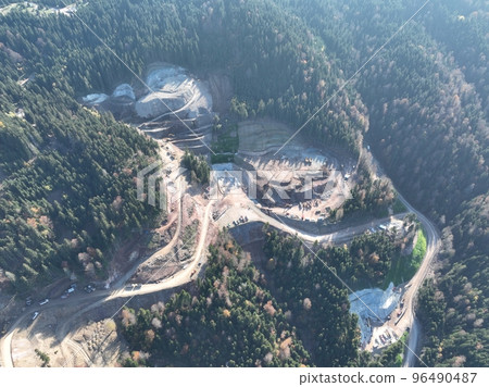 Industrial mine excavators are digging the soil in the construction site and loading trucks. Aerial drone top view. Industrial mine excavators are digging the soil in the construction site and loading trucks. Aerial drone top view. 96490487