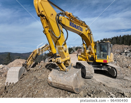 Industrial mine excavators are digging the soil in the construction site and loading trucks. Aerial drone top view. Industrial mine excavators are digging the soil in the construction site and loading trucks. Aerial drone top view. 96490490