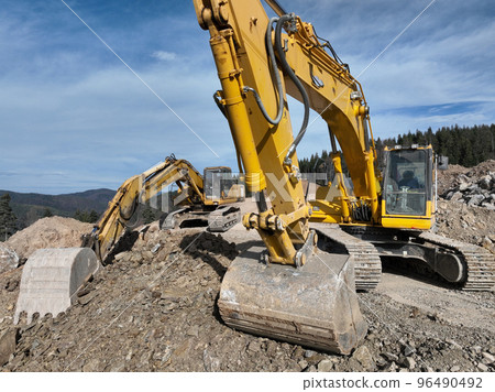 Industrial mine excavators are digging the soil in the construction site and loading trucks. Aerial drone top view.  96490492