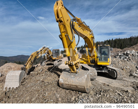 Industrial mine excavators are digging the soil in the construction site and loading trucks. Aerial drone top view. Industrial mine excavators are digging the soil in the construction site and loading trucks. Aerial drone top view. 96490501