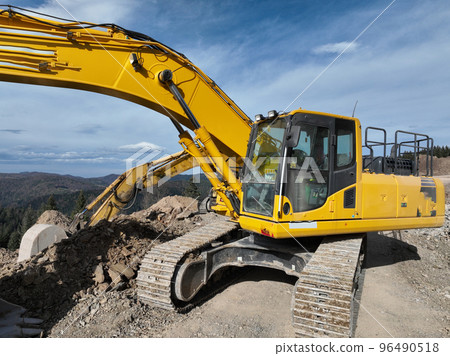 Industrial mine excavators are digging the soil in the construction site and loading trucks. Aerial drone top view.  96490518