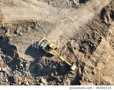 Industrial mine excavators are digging the soil in the construction site and loading trucks. Aerial drone top view. Industrial mine excavators are digging the soil in the construction site and loading trucks. Aerial drone top view. 96490534
