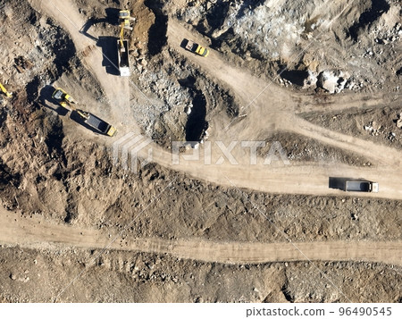 Industrial mine excavators are digging the soil in the construction site and loading trucks. Aerial drone top view. Industrial mine excavators are digging the soil in the construction site and loading trucks. Aerial drone top view. 96490545