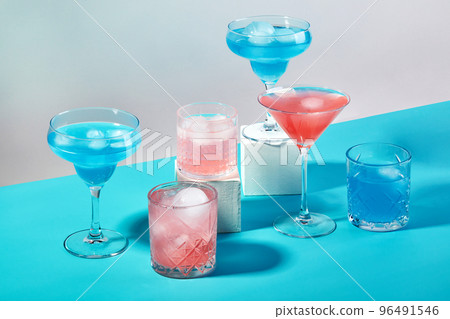 Multi-colored cocktails in glasses of different shapes on colored backgrounds with hard shadows 96491546
