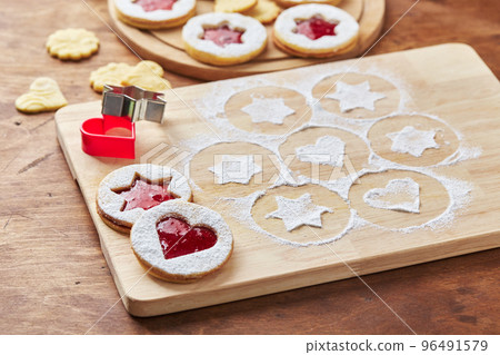Wooden cutting board with powdered sugar and Linzer cookies, baking decoration process Wooden cutting board with powdered sugar and Linzer cookies, baking decoration process 96491579