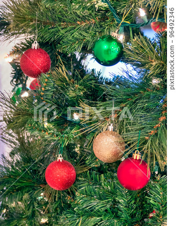 Red, golden, and green bauble on pine tree brenches 96492346