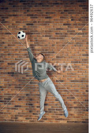 Concentrated footballer catching the football in the air Concentrated footballer catching the football in the air 96492637