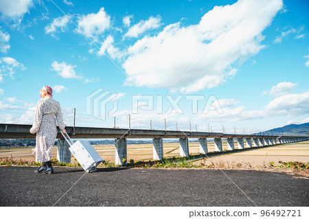 Pink-haired woman with a carry-on bag 96492721