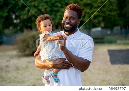 Joyous young man with his child in a park 96492797