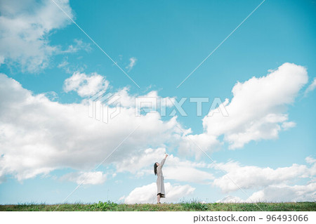 A woman with long hair reaching out under the vast blue sky A woman with long hair reaching out under the vast blue sky 96493066