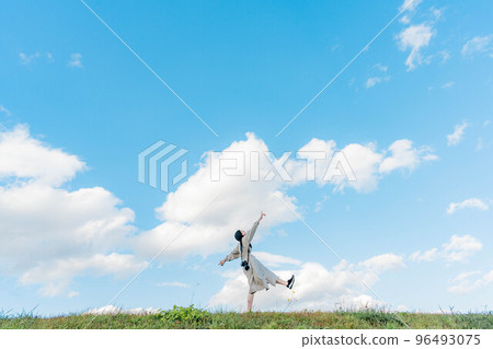 A woman with long hair reaching out under the vast blue sky A woman with long hair reaching out under the vast blue sky 96493075